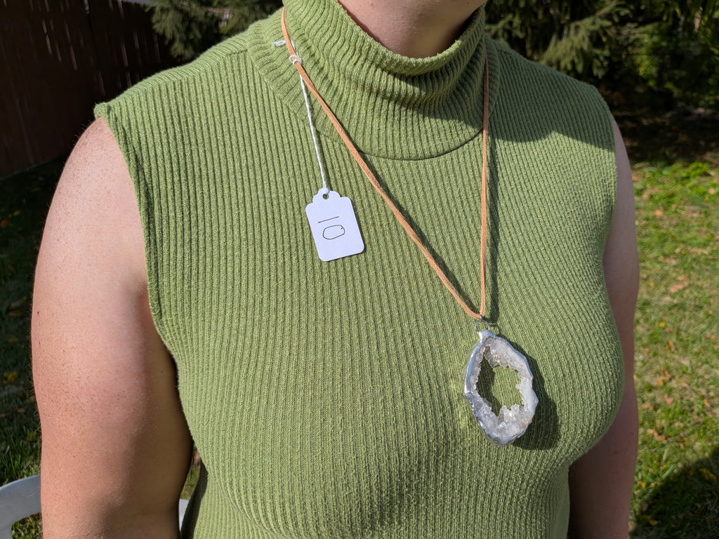 Open Sky geode necklace No. 010 worn over a green top, showing the pendant’s proportions and tan cord.
