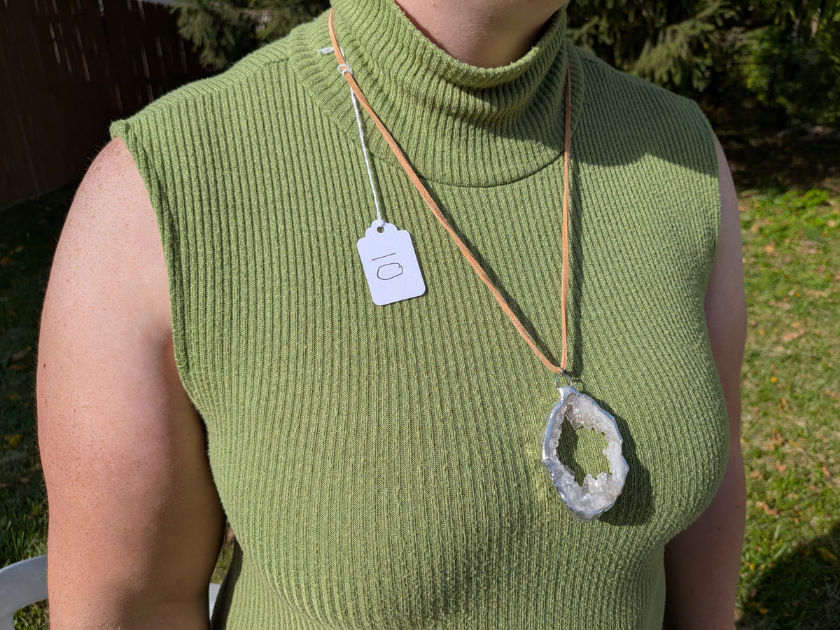 Open Sky geode necklace No. 010 worn over a green top, showing the pendant’s proportions and tan cord.