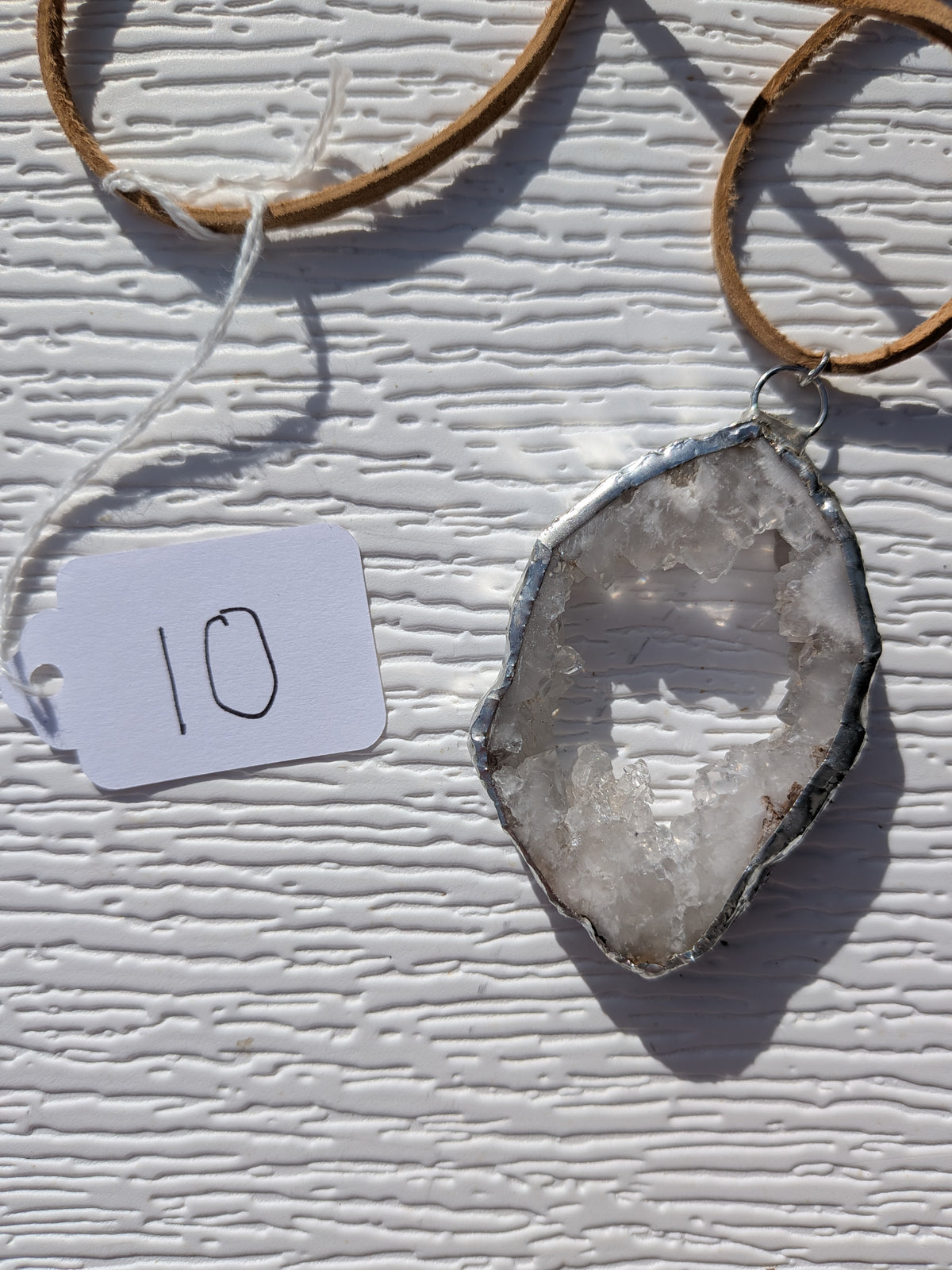 Front of Open Sky geode necklace No. 010, showing its natural crystal and stone pattern, handmade silver-tone edge, and tan cord.