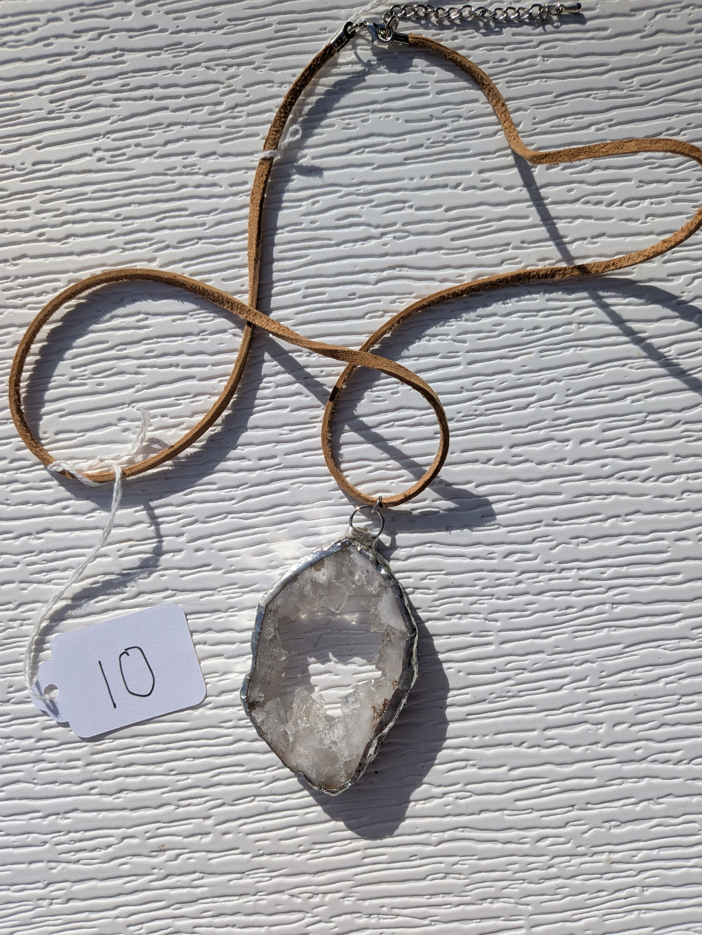 Full Open Sky geode necklace No. 010, showing the pendant, tan cord, and clasp.