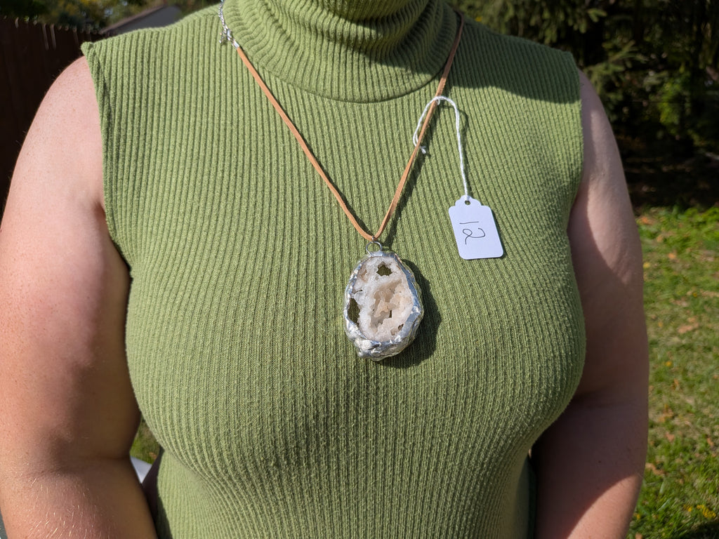 Honey Crystal Cavern geode necklace No. 012 worn over a green top, showing the pendant’s proportions and tan cord.
