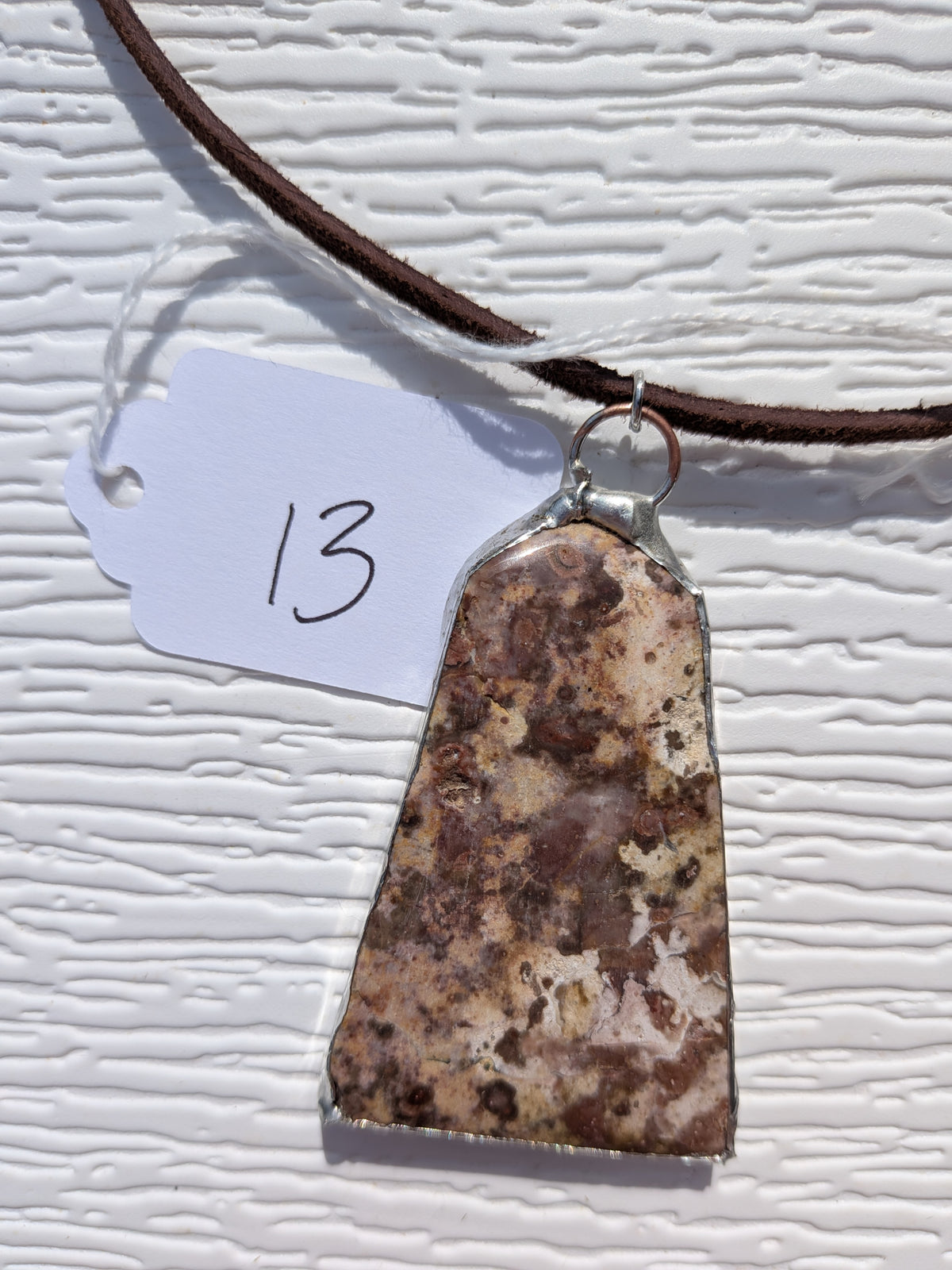 Front of Earth Mosaic necklace No. 013, showing its natural stone pattern, handmade silver-tone edge, and dark brown cord.