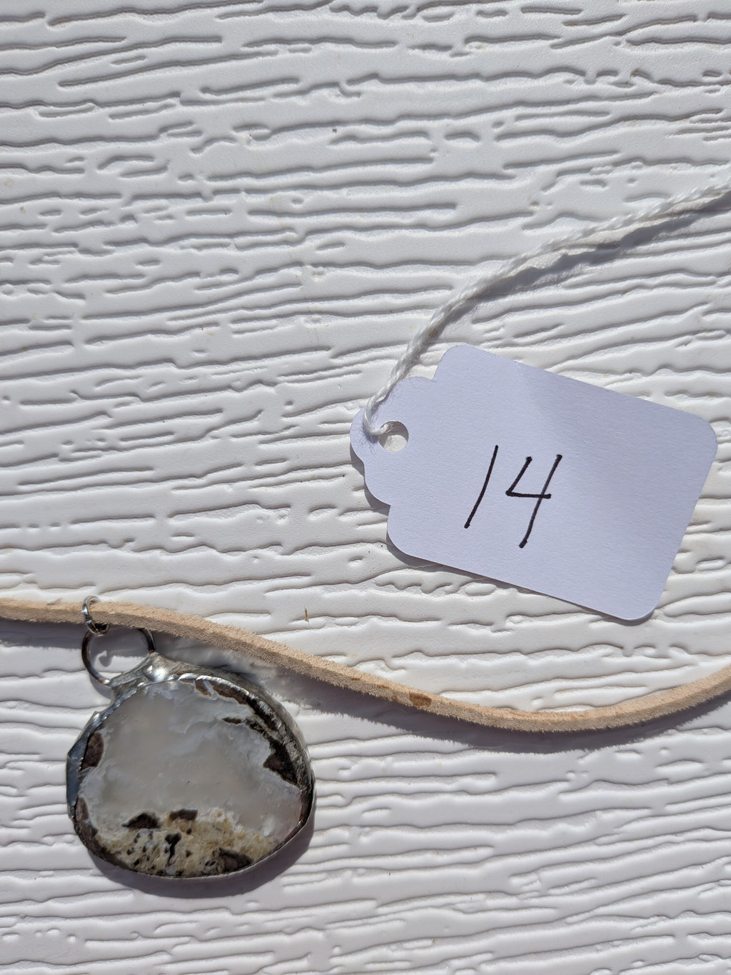 Front of Cloud Meadow necklace No. 014, showing its natural stone pattern, handmade silver-tone edge, and tan cord.