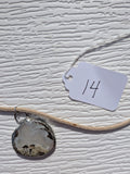 Front of Cloud Meadow necklace No. 014, showing its natural stone pattern, handmade silver-tone edge, and tan cord.