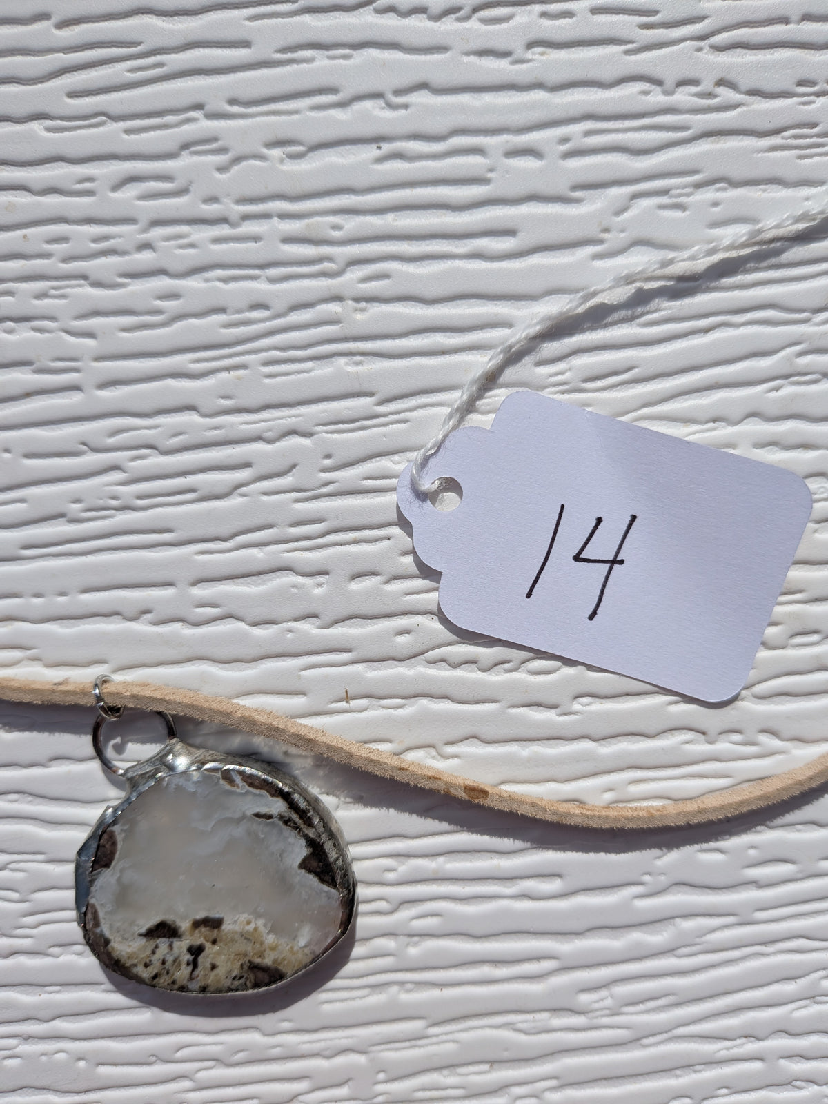 Front of Cloud Meadow necklace No. 014, showing its natural stone pattern, handmade silver-tone edge, and tan cord.
