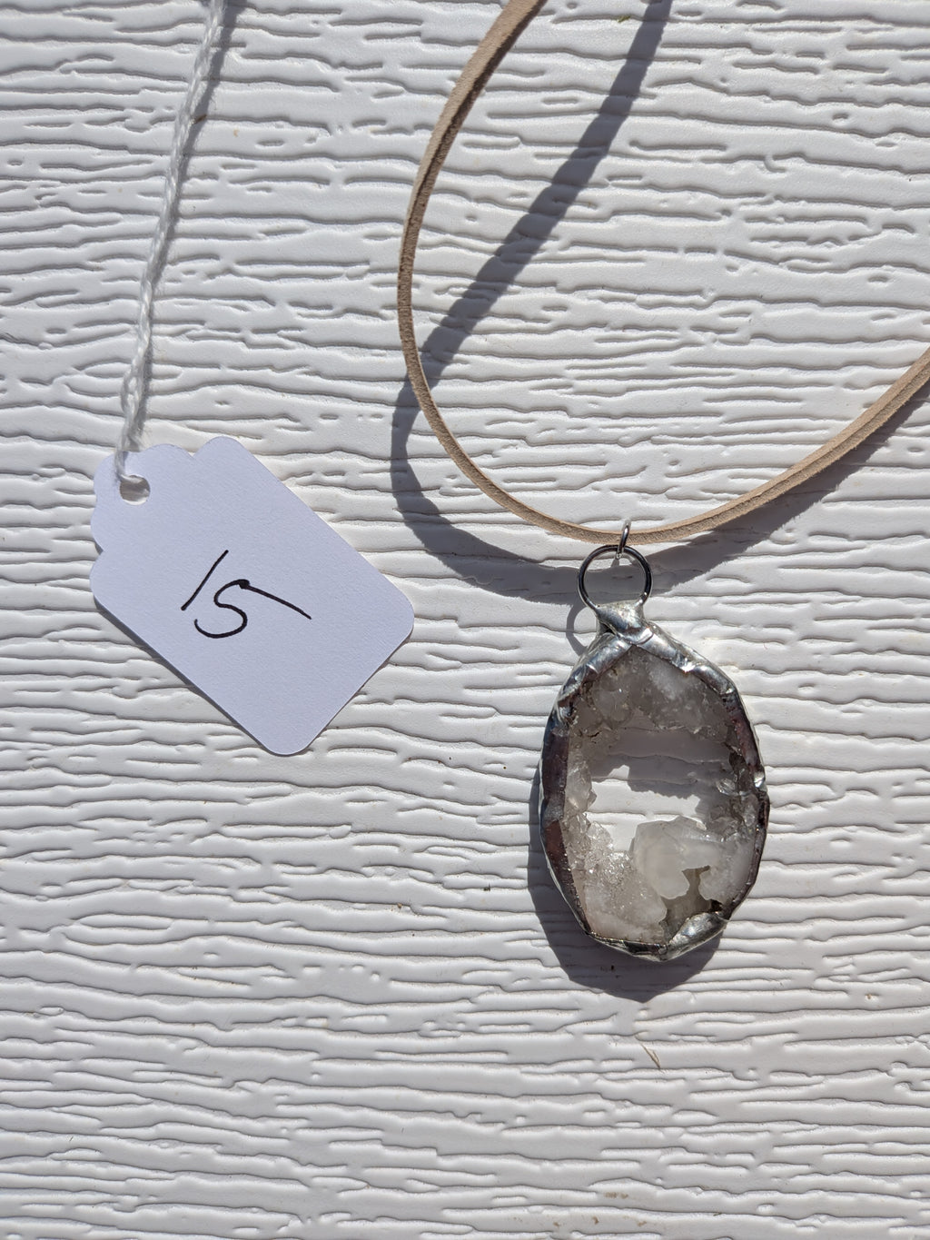 Front of Crystal Pool necklace No. 015, showing its natural stone pattern, handmade silver-tone edge, and tan cord.