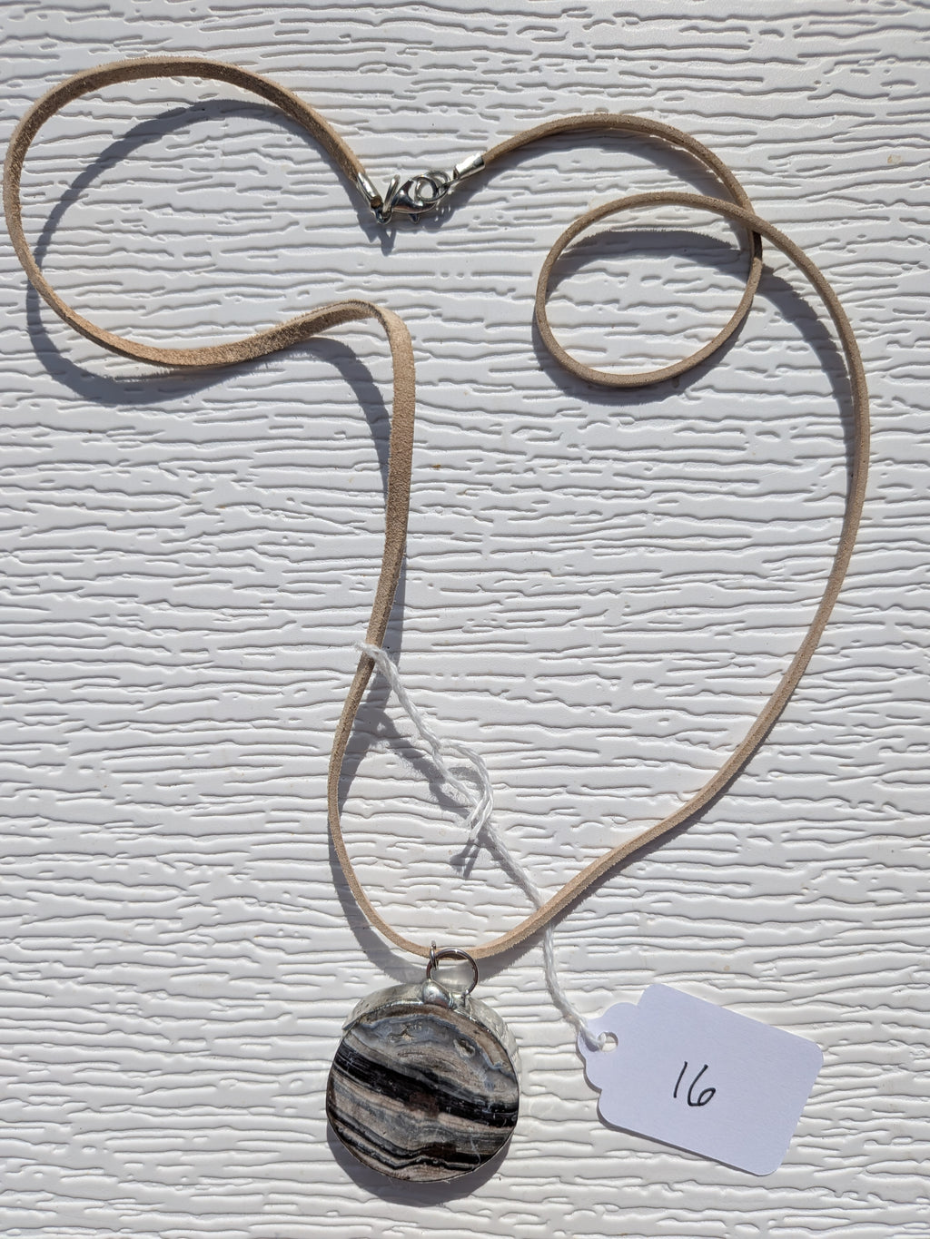 Full River Strata necklace No. 016, showing the pendant, tan cord, and clasp.