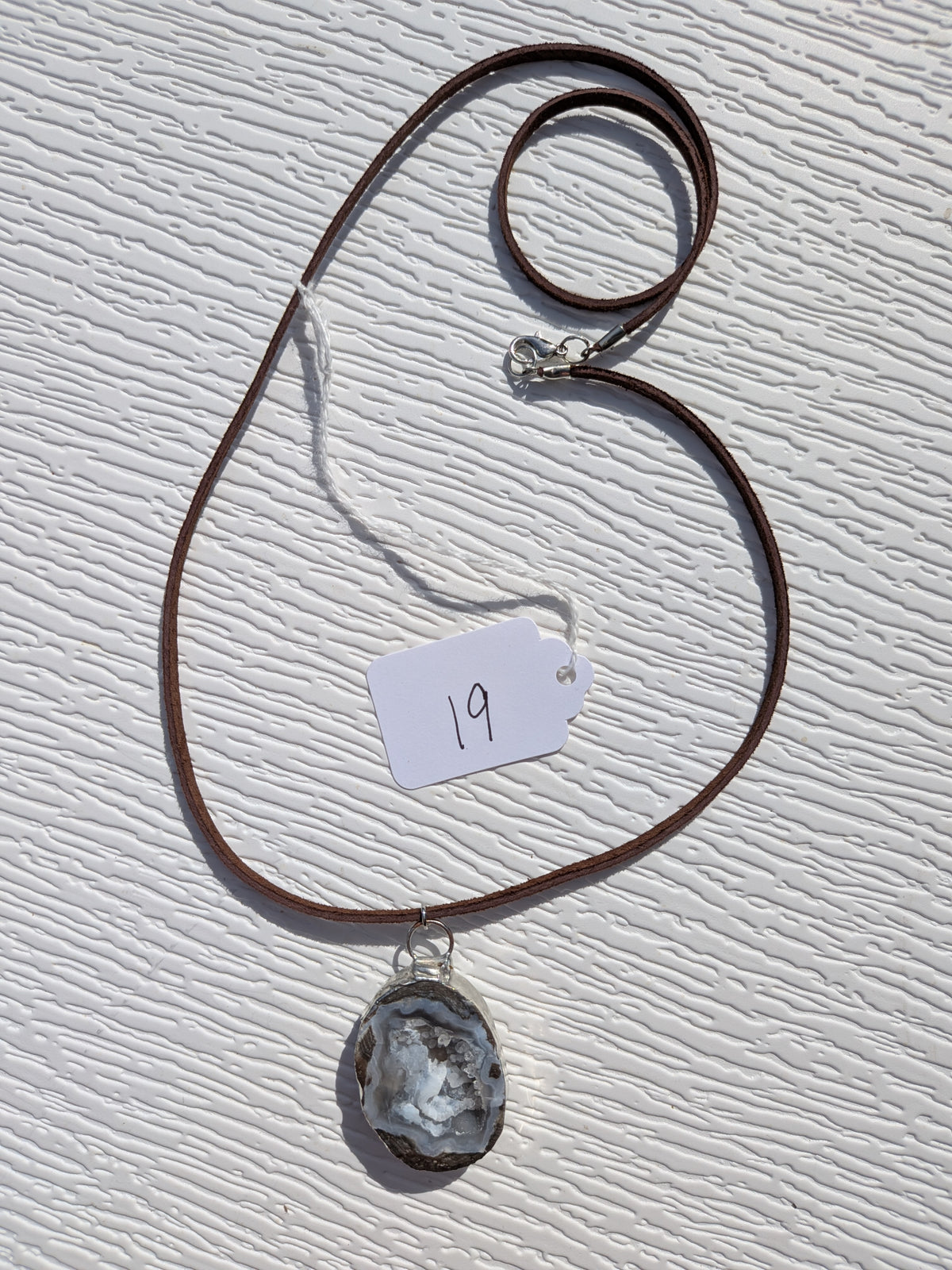 Full Storm Crystal Cavern necklace No. 019, showing the pendant, dark brown cord, and clasp.
