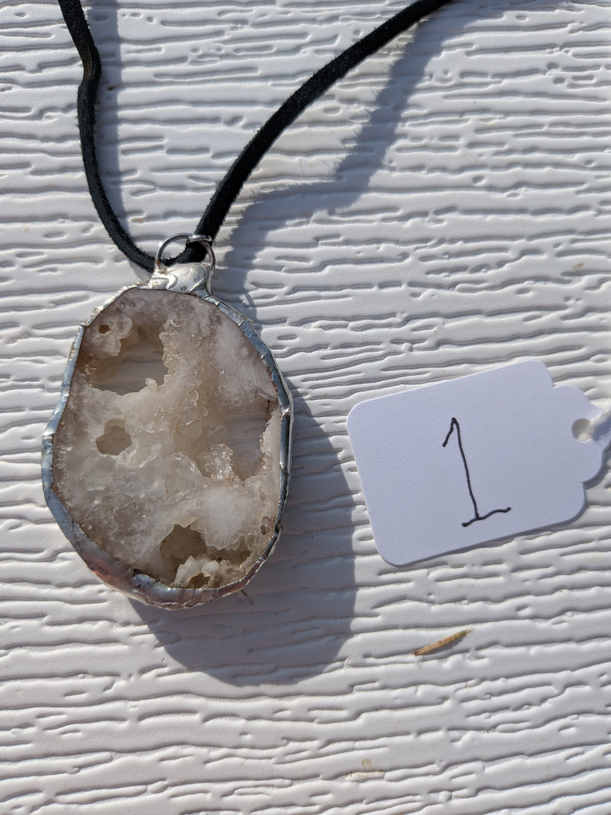 Back view: Crystal Cavern geode slice necklace No. 001 by Made by Haylie, with handmade silver-tone edging and a black cord.