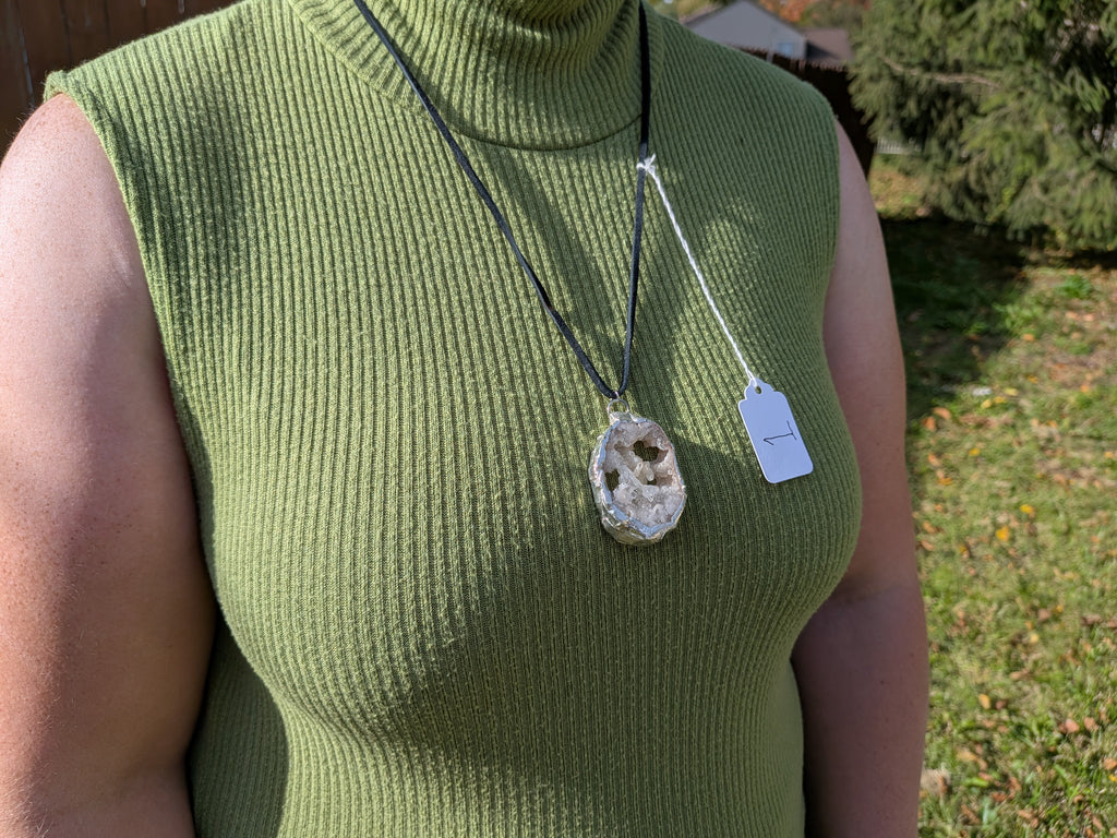 Crystal Cavern geode necklace No. 001 worn over a green top, showing the pendant’s proportions and black cord.