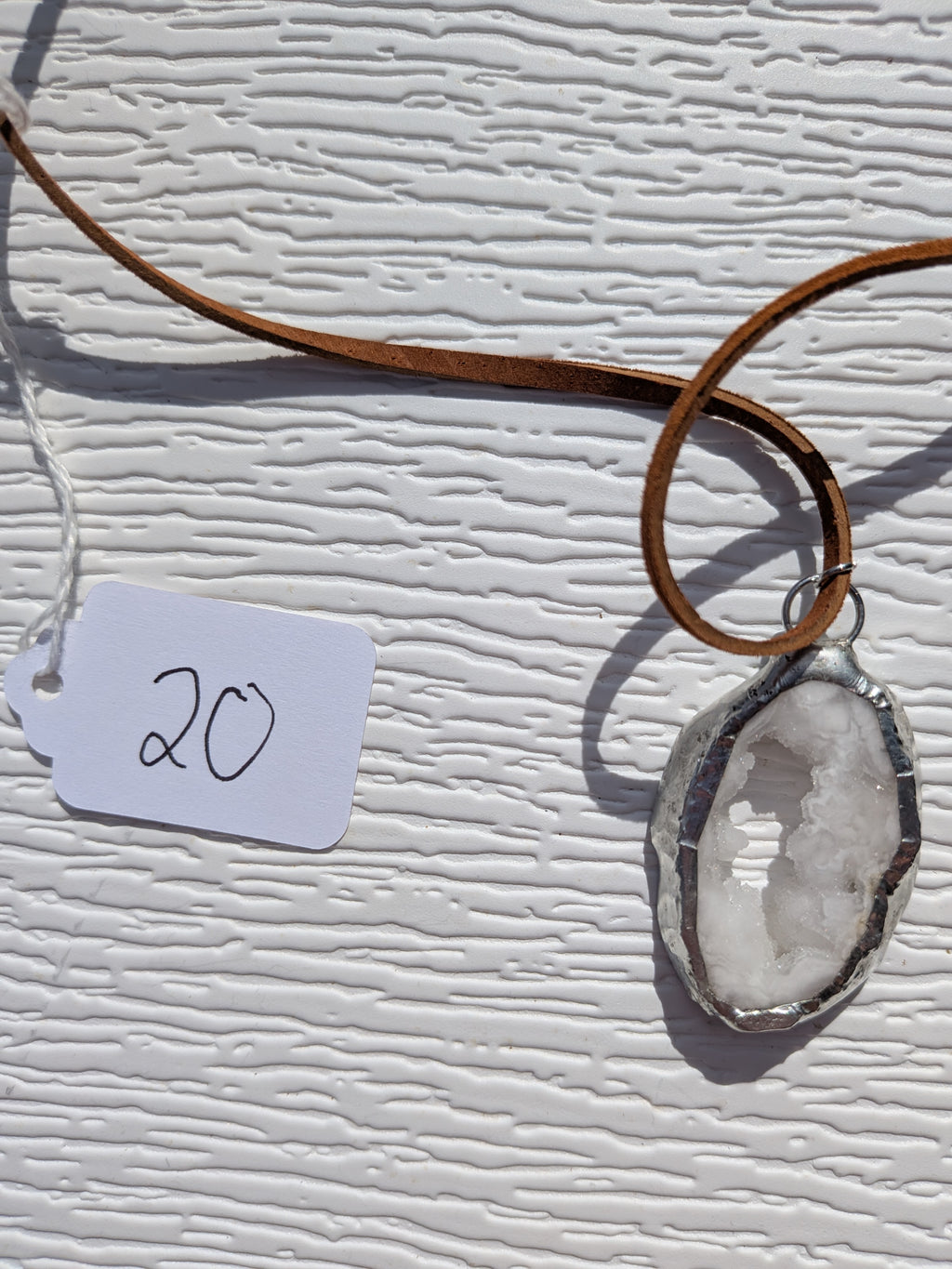 Front of Snowlight Window necklace No. 020, showing its natural stone pattern, handmade silver-tone edge, and warm brown cord.