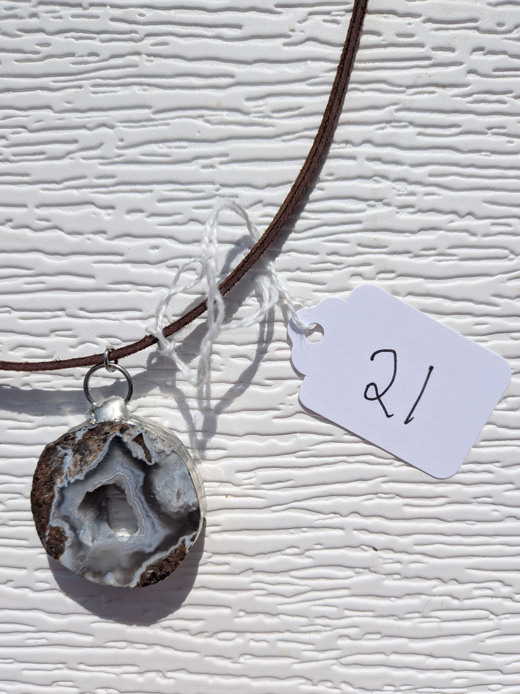Front of Mountain Hollow necklace No. 021, showing its natural stone pattern, handmade silver-tone edge, and dark brown cord.