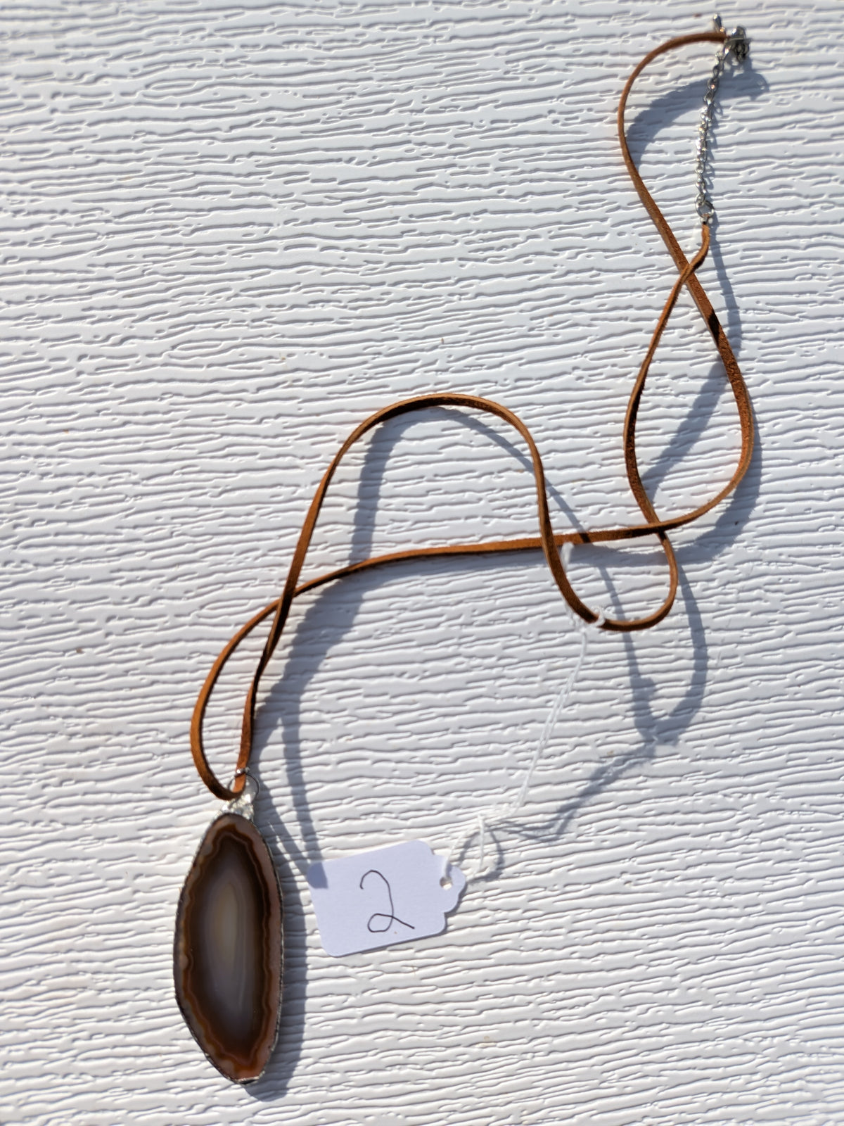 Full Earthline Banded geode necklace No. 002, showing the elongated brown and gray pendant, brown cord, clasp, and extension chain.
