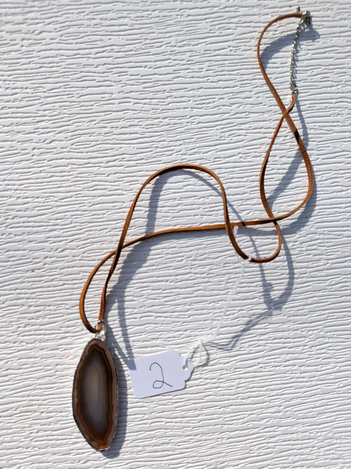 Full Earthline Banded geode necklace No. 002, showing the elongated brown and gray pendant, brown cord, clasp, and extension chain.