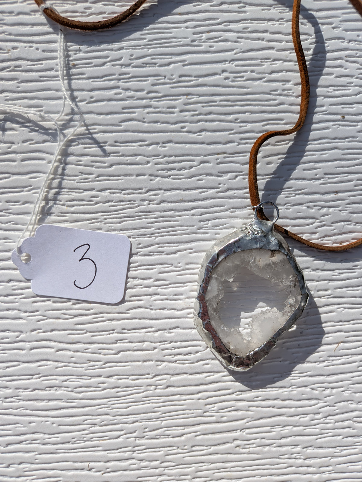 Back of Crystal Window geode necklace No. 003, showing its natural stone contours, central opening, and handmade silver-tone edge.
