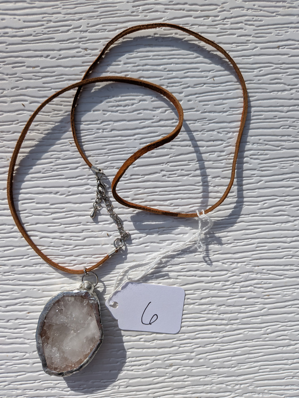 Full Frosted Crystal geode necklace No. 006, showing the pendant, brown cord, and clasp.