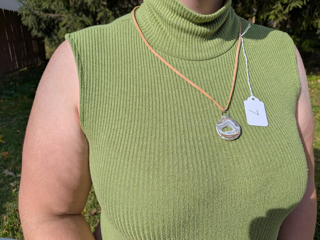 Earth Rings geode necklace No. 007 worn over a green top, showing the pendant’s proportions and tan cord.