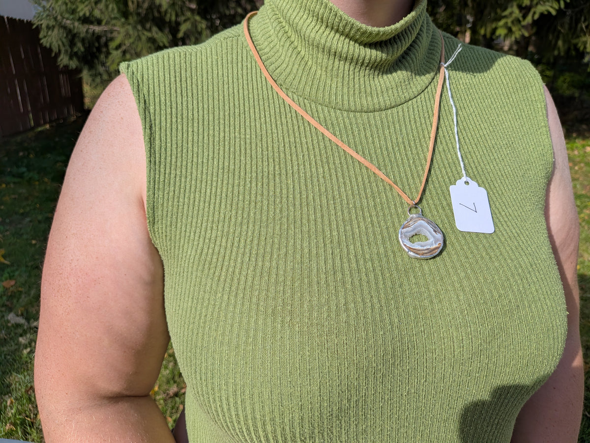 Earth Rings geode necklace No. 007 worn over a green top, showing the pendant’s proportions and tan cord.