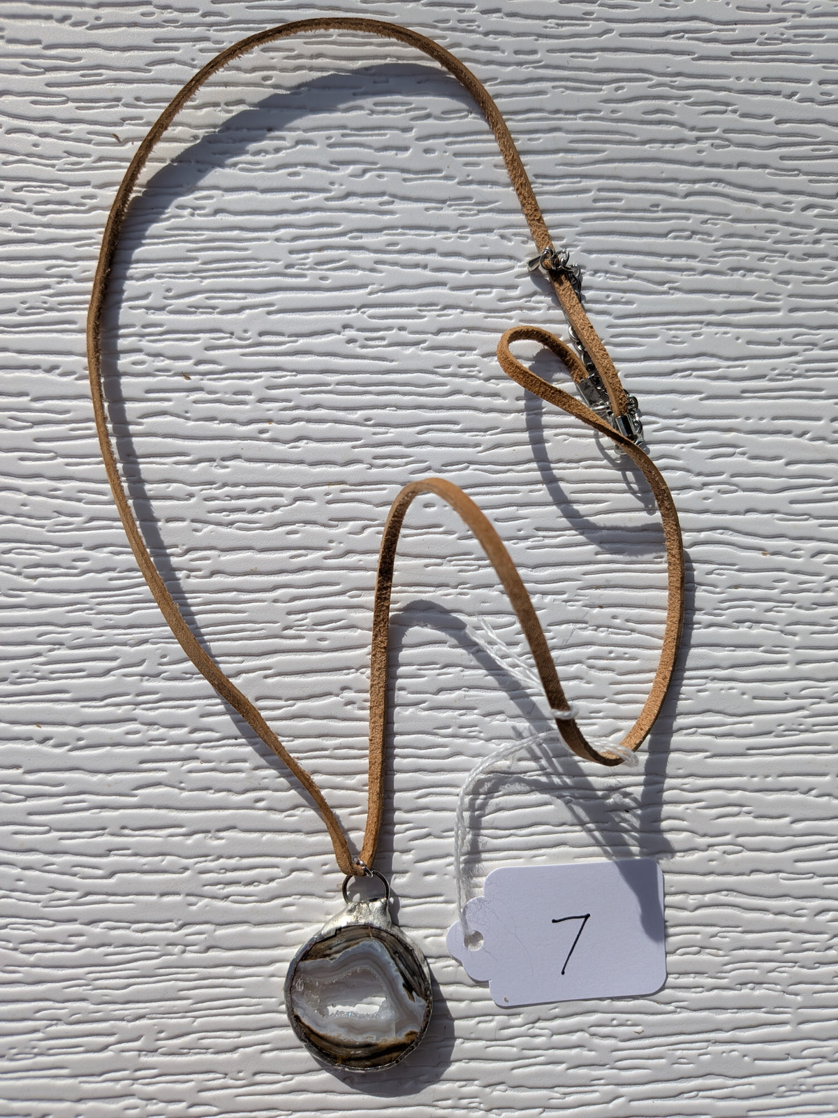 Full Earth Rings geode necklace No. 007, showing the pendant, tan cord, and clasp.