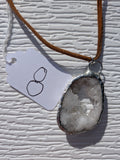 Front of Little Crystal Window geode necklace No. 008, showing its natural crystal and stone pattern, handmade silver-tone edge, and brown cord.
