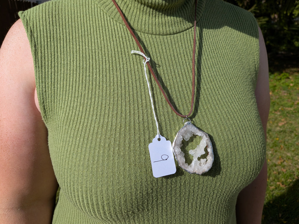 Crystal Bridge geode necklace No. 009 worn over a green top, showing the pendant’s proportions and dark brown cord.